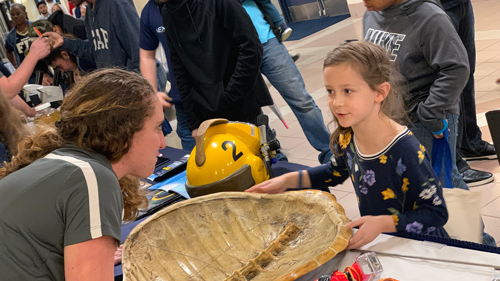 Marine scientist showing a turtle shell to a 7-year-old girl