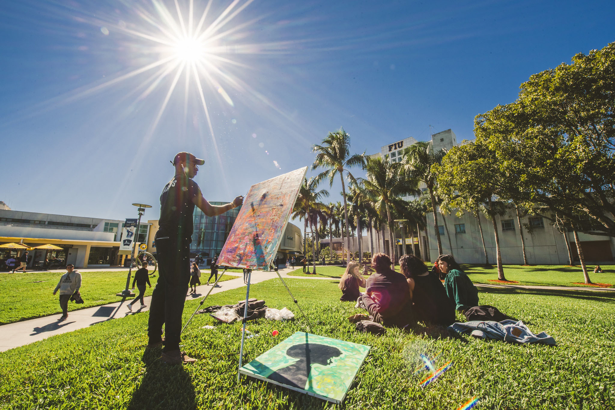 Student paints on a canvas outside of FIU's Graham Center