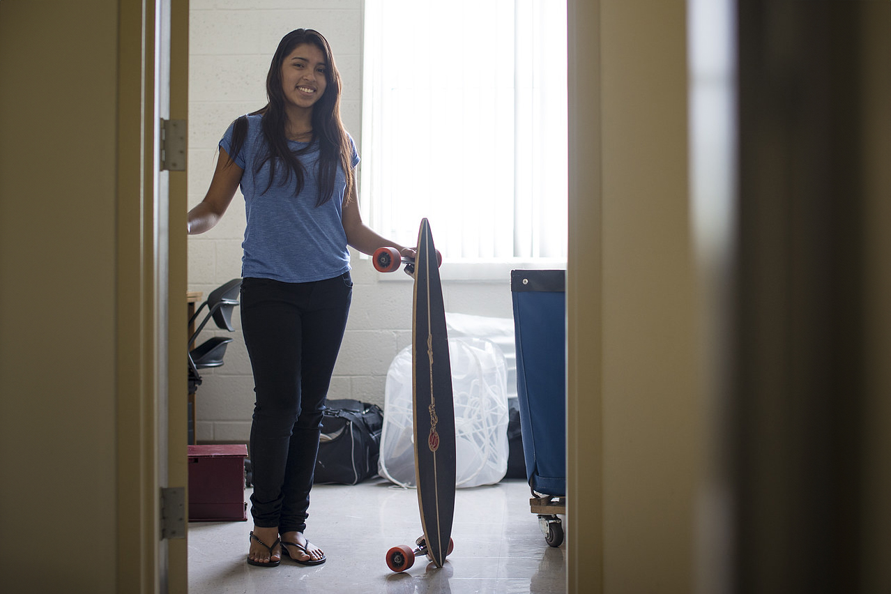 Student holds skateboard inside her dorm room
